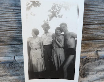 May include: Black and white photograph of four people standing outdoors. Two women and two men are smiling at the camera. The women are wearing dresses and the men are wearing shirts and pants. The photo is likely from the 1920s or 1930s.