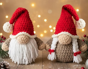 May include: Two handmade crochet Christmas gnomes. Each gnome has a red hat with a white pom-pom, a beige face, and a long white or braided beard. The gnomes are on a wooden surface with festive decorations.