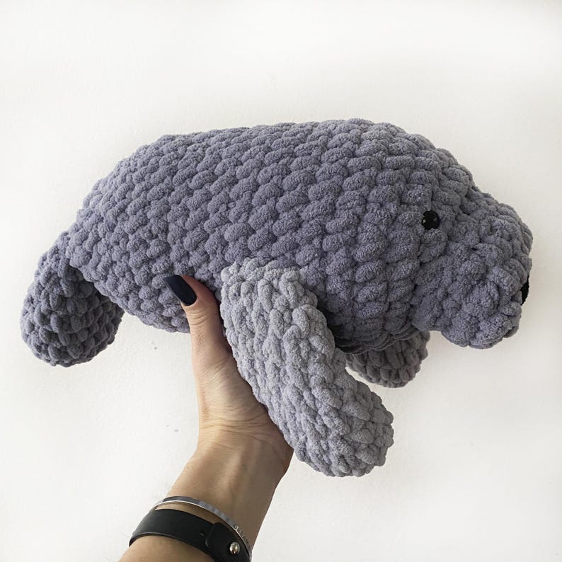 Puede incluir: Un juguete de peluche de manat&iacute; de crochet gris. El juguete tiene una superficie texturizada y ojos negros.
