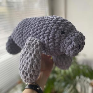 Puede incluir: Un juguete de peluche de manat&iacute; gris tejido a crochet. El manat&iacute; est&aacute; hecho con un hilo texturizado y tiene un aspecto suave y abrazable.