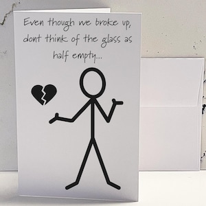 May include: A white card with black text and a stick figure illustration. The text reads "Even though we broke up, don't think of the glass as half empty..." and a broken heart is drawn next to the stick figure.