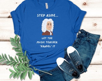 May include: A royal blue t-shirt with a white graphic of a man with a white wig and the text "Step aside... Let the music teacher 'Handel' it."