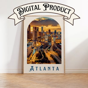 May include: A digital print of an aerial view of Atlanta, Georgia at sunset. The city skyline is visible in the distance, with a highway intersection in the foreground. The print is framed in a white frame with a rounded arch top and the word "ATLANTA" printed below the image.