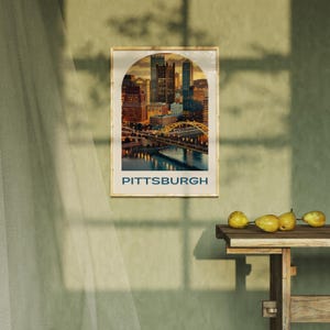 K&ouml;nnte beinhalten: Ein Vintage-Poster mit einem Foto der Skyline von Pittsburgh bei Sonnenuntergang. Das Poster hat einen braunen Rahmen und den Text "PITTSBURGH" in blauen Buchstaben unten.