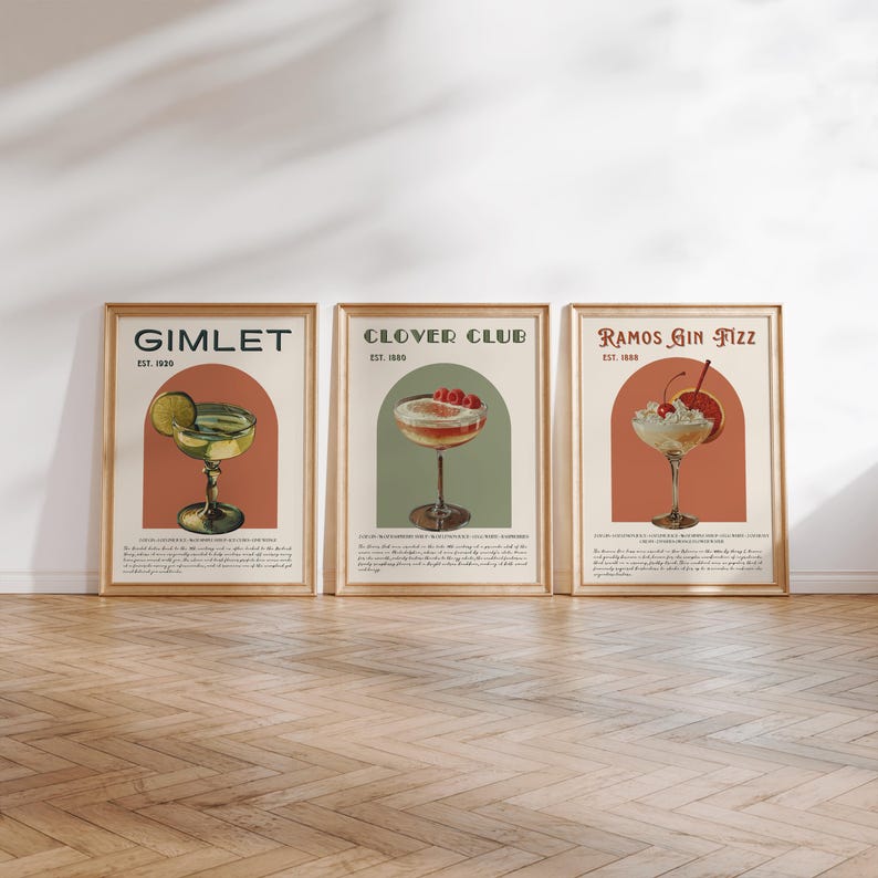 May include: Three vintage-style cocktail posters with illustrations of a Gimlet, Clover Club, and Ramos Gin Fizz. Each poster features a colorful illustration of the cocktail, the name of the drink, and the year it was established.