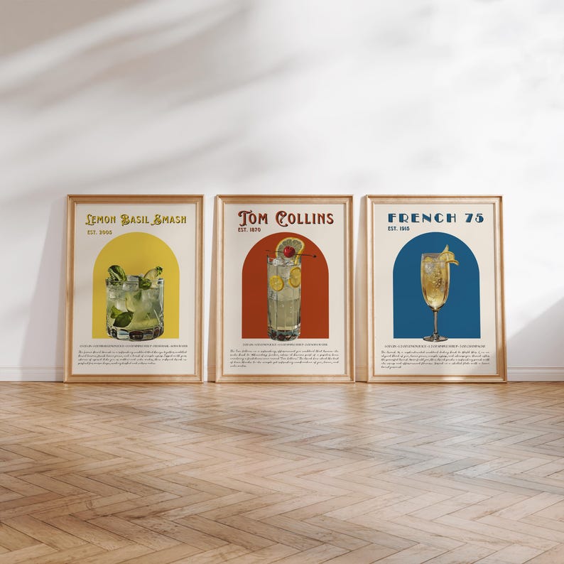 May include: Three vintage-style cocktail posters with illustrations of Lemon Basil Smash, Tom Collins, and French 75 cocktails. Each poster features a yellow, red, and blue archway with the name of the cocktail and its establishment date.