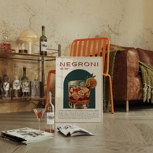 Living area with an orange metal chair, bar cart, and vintage posters; featuring a vintage-style poster of a classic Negroni cocktail in a glass with ice and an orange slice, the style is retro. The poster details the history and ingredients.