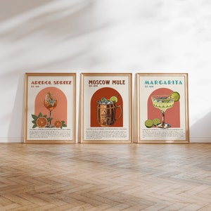 May include: Three vintage-style cocktail posters with illustrations of Aperol Spritz, Moscow Mule, and Margarita drinks. Each poster features a colorful illustration of the drink, the drink's name, and the year it was established.