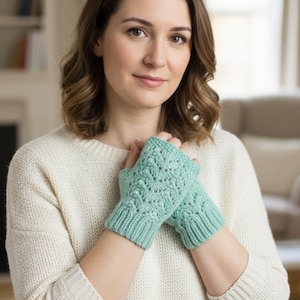 Puede incluir: Un par de guantes sin dedos de color verde azulado claro con un patrón de punto detallado. Los guantes están hechos de un hilo suave y tienen un puño acanalado. Los guantes están diseñados para mantener las manos calientes mientras dejan los dedos libres.