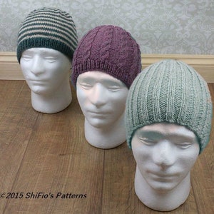 May include: Three knitted hats in different colors and patterns. The hats are displayed on white mannequin heads. The hats are a striped blue and white hat, a purple cable knit hat, and a light blue ribbed hat.