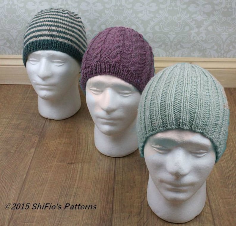May include: Three knitted hats in different colors and patterns. The hats are displayed on white mannequin heads. The hats are a striped blue and white hat, a purple cable knit hat, and a light blue ribbed hat.