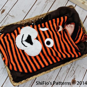 May include: A baby swaddled in a black and orange striped knitted sleeping bag with a crocheted animal face. The sleeping bag has a matching hat with a pom-pom on top. ShiFi'o's Patterns © 2014.