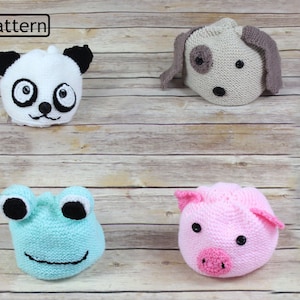 May include: Four crocheted animal hats on a wooden background. The hats are a panda, a dog, a frog, and a pig. The hats are all different colors and have different facial features.