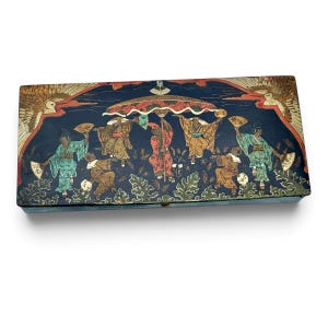 May include: A rectangular box with a dark blue lid featuring a painted scene of figures in traditional attire holding fans under a large umbrella. The design includes stylised birds in the upper corners and green foliage along the bottom edge.