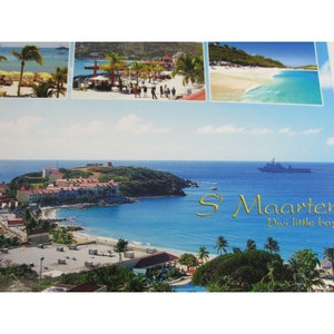 Può includere: Una cartolina con una vista panoramica di un'isola tropicale con una baia turchese, un piccolo paese e una nave in lontananza. Il testo sulla cartolina recita "St. Maarten Divi little bay".