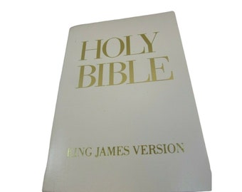May include: A white leather-bound Holy Bible with gold lettering on the cover. The title reads "HOLY BIBLE" and the subtitle reads "KING JAMES VERSION".