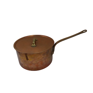 May include: A copper saucepan with a lid and a brass handle. The saucepan has a worn, aged look.