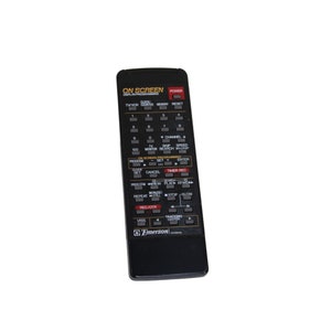 May include: Black remote control with a red and white display screen. The remote has buttons for TV, monitor, search, skip, speed, program, clock, set, cancel, timer rec, rew, play, ffwd, repeat, still, stop, slow, rec/otr, viss, and tracking center. The remote has the word "Emerson" printed on it.