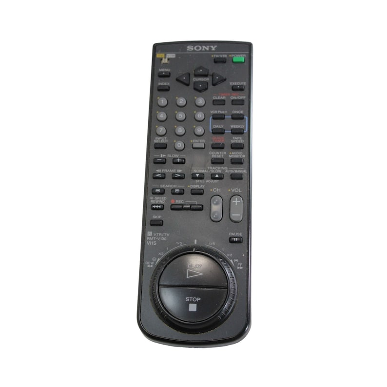 Puede incluir: Un mando a distancia negro Sony para VCR con un bot&oacute;n circular en el centro. El bot&oacute;n tiene un s&iacute;mbolo de reproducci&oacute;n y un bot&oacute;n de parada. El mando a distancia tiene una variedad de botones, incluidos los botones de canal arriba y abajo, volumen arriba y abajo, y un bot&oacute;n de pausa.