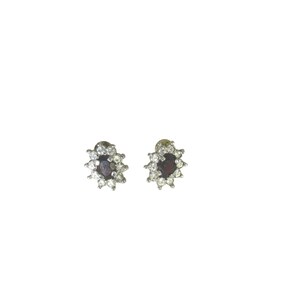 May include: A pair of silver earrings with a small, dark purple gemstone surrounded by a halo of clear rhinestones.