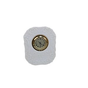 May include: White porcelain clock with a gold-tone frame and Roman numeral face.