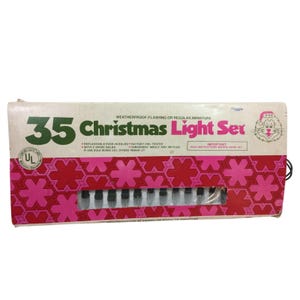 May include: A rectangular cardboard box for a 35 Christmas Light Set. The box features a white background with a pink and red geometric snowflake pattern. Text includes 35 Christmas Light Set, UL label, and instructions for bulb replacement.