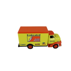 Könnte beinhalten: Gelber und orangefarbener Spielzeug-Lieferwagen mit der Aufschrift "Federated Auto Parts" an der Seite. Der LKW hat ein rotes Dach und ein schwarzes Federal Mogul-Logo.