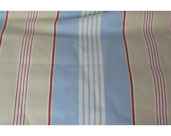 Può includere: Tessuto a righe con bande alternate di azzurro, beige e bianco, con sottili righe rosse che attraversano le bande beige.