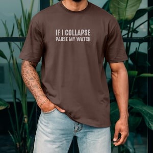 May include: A brown t-shirt with the text "IF I COLLAPSE PAUSE MY WATCH" printed on the front.