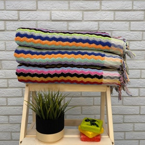 Peut inclure: Une pile de serviettes rayées colorées avec un motif ondulé. Les serviettes sont pliées et empilées sur une étagère en bois. Une petite plante en pot et une pile de savons sont également sur l'étagère.