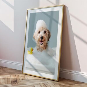 May include: A framed print featuring a happy dog in a bubble bath with a yellow rubber duck. The dog has a foamy bubble hat and is smiling. The frame is gold, and the background is a light blue.