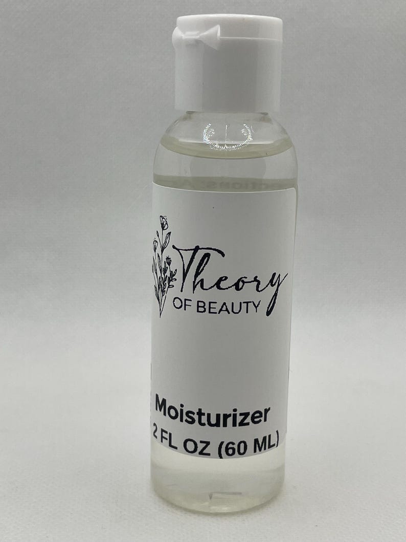 May include: A clear plastic bottle with a white cap, containing a clear liquid. The label reads "Theory of Beauty" with a floral design and "Moisturizer 2 FL OZ (60 ML)".