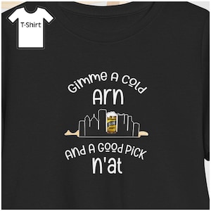 May include: Black t-shirt with white text that reads "Gimme a cold Arn and a good pick n'at." The design includes a beer glass and a city skyline silhouette. A small graphic of a t-shirt is in the upper left corner.