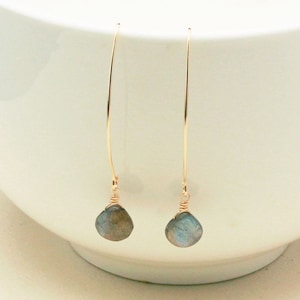 May include: A pair of gold dangle earrings with a blue-grey gemstone on each earring.