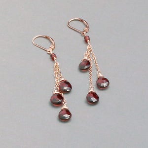 May include: A pair of dangle earrings with multiple red gemstone drops and gold chains.