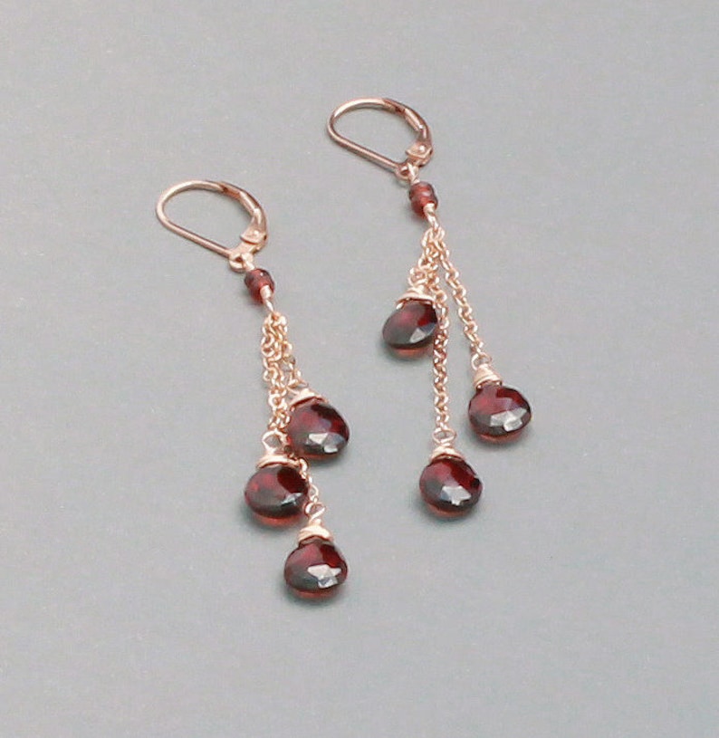 May include: A pair of dangle earrings with multiple red gemstone drops and gold chains.