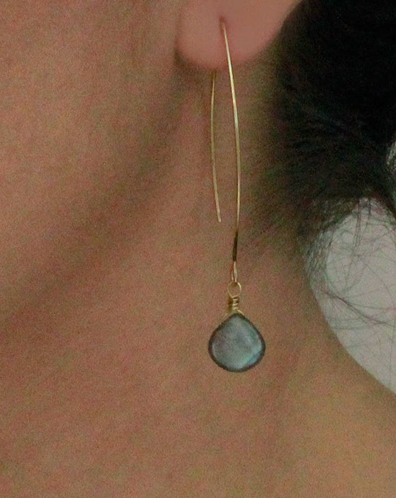 May include: Gold dangle earrings with a teardrop-shaped blue gemstone.