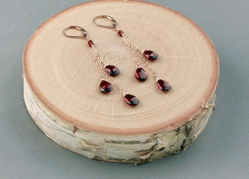 May include: A pair of dangle earrings with multiple strands of gold chain and red gemstone drops.