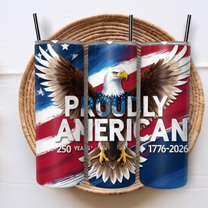May include: Three stainless steel tumblers with black straws, featuring an American flag design and a bald eagle. The text "PROUDLY AMERICAN" is displayed, with "250 YEARS 1776-2026" below. The tumblers are set in a woven basket.