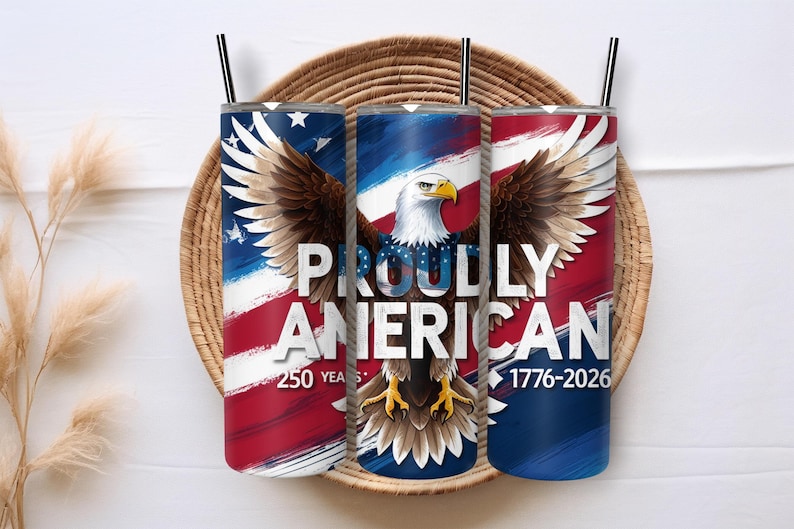 May include: Three stainless steel tumblers with black straws, featuring an American flag design and a bald eagle. The text "PROUDLY AMERICAN" is displayed, with "250 YEARS 1776-2026" below. The tumblers are set in a woven basket.