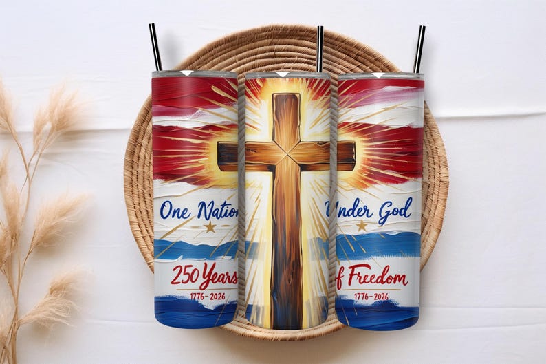 May include: Three stainless steel tumblers with black straws, featuring a patriotic design. The design includes a wooden cross, red and blue stripes, and the text "One Nation Under God" and "250 Years of Freedom 1776-2026". The tumblers are displayed on a woven tray.