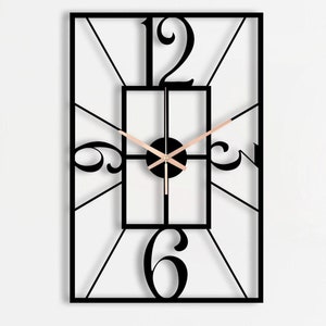 Może przedstawiać: Czarny metalowy zegar ścienny z rzymskimi cyframi i kwadratową ramą. Zegar jest zamontowany na białej ścianie z czarnym metalowym wieszakiem na klucze, przedstawiającym sylwetkę paryskiego krajobrazu miejskiego.