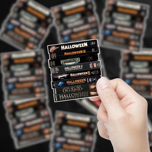 May include: A stack of VHS tapes of the Halloween horror movie franchise. The tapes are arranged from top to bottom in order of release: Halloween, Halloween II, Halloween III: Season of the Witch, Halloween 4: The Return of Michael Myers, Halloween 5: The Revenge of Michael Myers, Halloween: The Curse of Michael Myers, and Halloween H20: 20 Years Later.