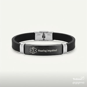 May include: A black silicone medical alert bracelet featuring a central black metal plate with a silver Star of Life symbol and the text Hearing Impaired engraved on it. The bracelet includes silver-toned metal accents and a secure metal clasp.