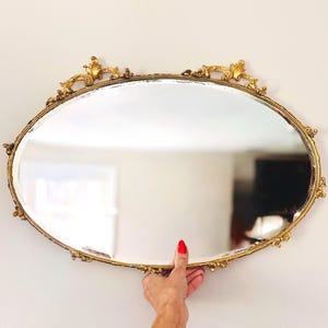 Large antique oval vanity tray — gilt metal frame, embossed sides, mirrored surface