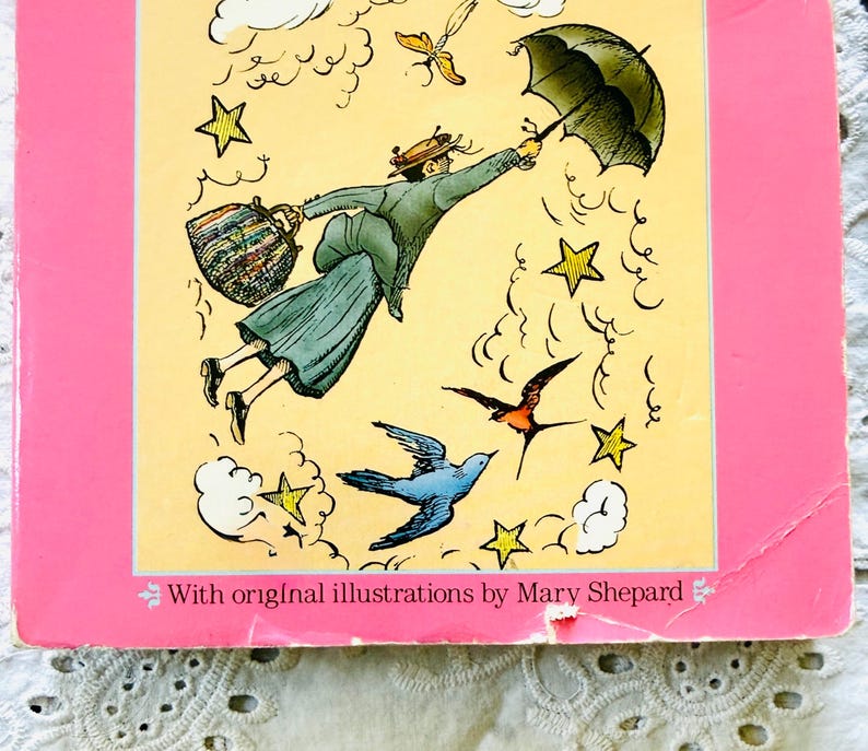 Puede incluir: Una portada de libro con borde rosa y panel central amarillo. Una ilustraci&oacute;n muestra a una figura con abrigo y sombrero volando con un paraguas negro y un bolso estampado, rodeada de estrellas amarillas, nubes blancas y dos p&aacute;jaros. El texto dice: With original illustrations by Mary Shepard.