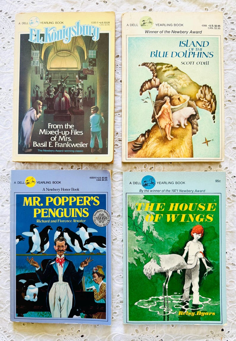 Puede incluir: Cuatro libros de bolsillo vintage Dell Yearling con portadas ilustradas: From the Mixed-up Files of Mrs. Basil E. Frankweiler, Island of the Blue Dolphins, Mr. Popper's Penguins y The House of Wings, cada uno con ilustraciones coloridas.