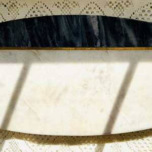 May include: Rectangular marble serving board with a dark blue and white marbled top section, separated by a thin gold band from the white marble base. The board has rounded corners and is ideal for serving appetizers.