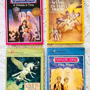 Puede incluir: Cuatro libros de bolsillo de Madeleine L'Engle: A Wrinkle in Time con borde rosa, A Wind in the Door con portada amarilla, A Swiftly Tilting Planet con portada verde y Many Waters con borde azul, todos con ilustraciones de fantas&iacute;a.