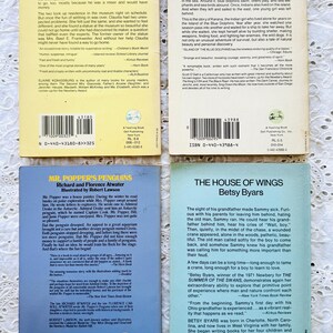 Puede incluir: Cuatro libros de bolsillo dispuestos en una cuadr&iacute;cula, cada uno con una contraportada de color claro con res&uacute;menes impresos, biograf&iacute;as de autores y c&oacute;digos de barras. Los t&iacute;tulos incluyen From the Mixed-Up Files of Mrs. Basil E. Frankweiler, Island of the Blue Dolphins, Mr. Popper's Penguins y The House of Wings.